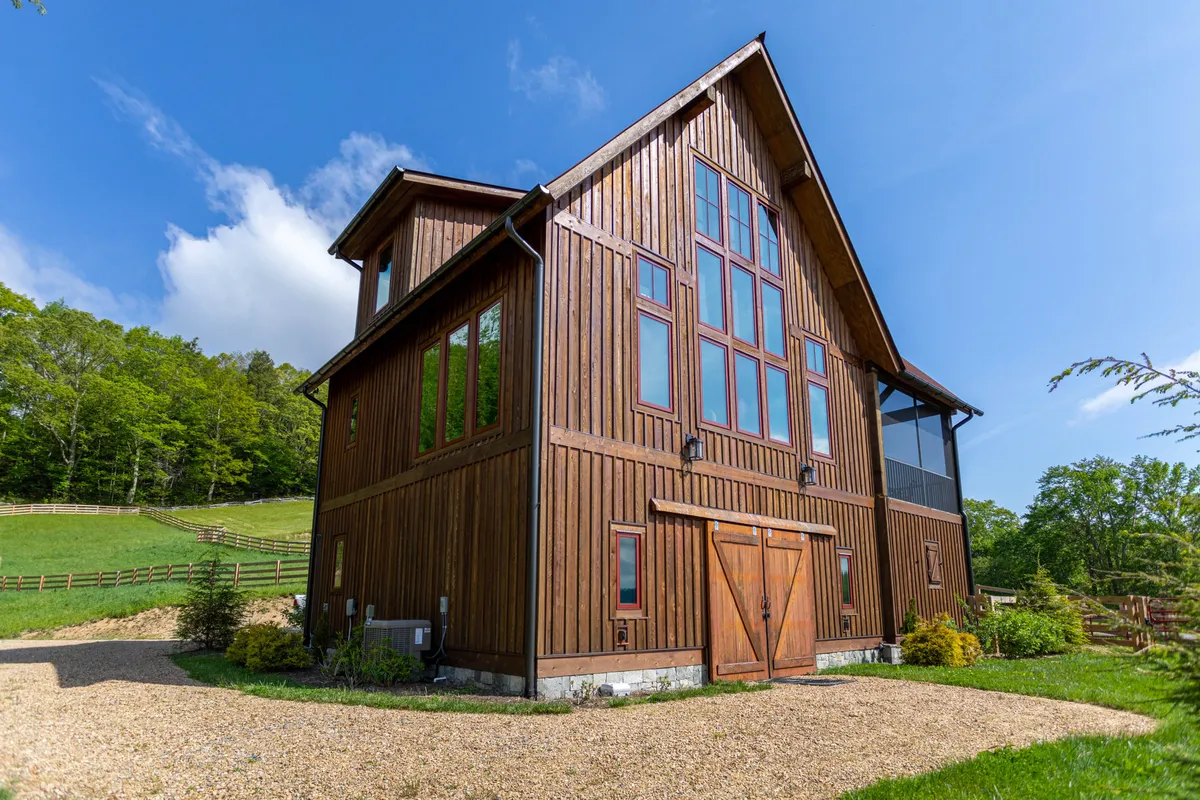 This exterior shot highlights a striking wooden structure with expansive glass windows overlooking a natural landscape. The peaceful mood suggests quiet mornings or evenings spent enjoying mountain vistas from the comfort of the porch, perfectly embodying the tranquil, retreat-like quality described in the text.
