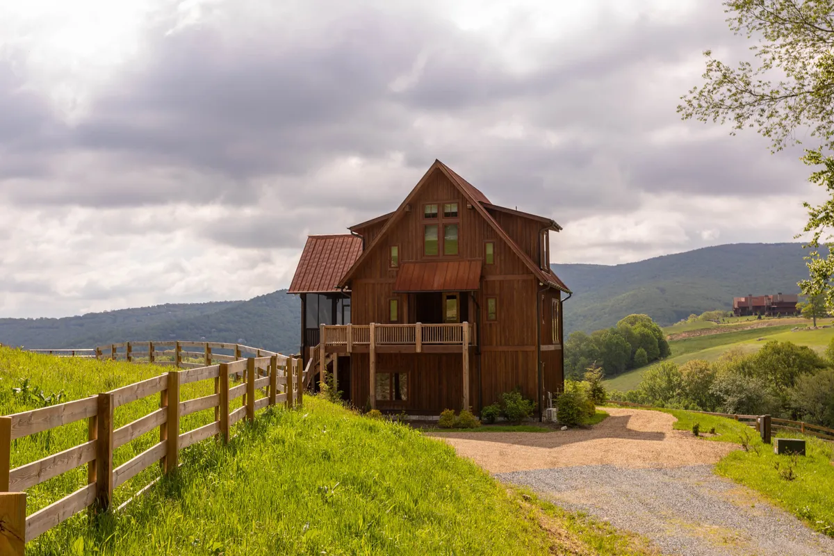 This photo captures the wooden house, rustic fence, and rolling hills surrounding Eagles Nest. The inviting porch and open landscape suggest spaces for gatherings, relaxation, and connecting with nature, while the golden hour lighting evokes both summer evenings and cozy winter moments.