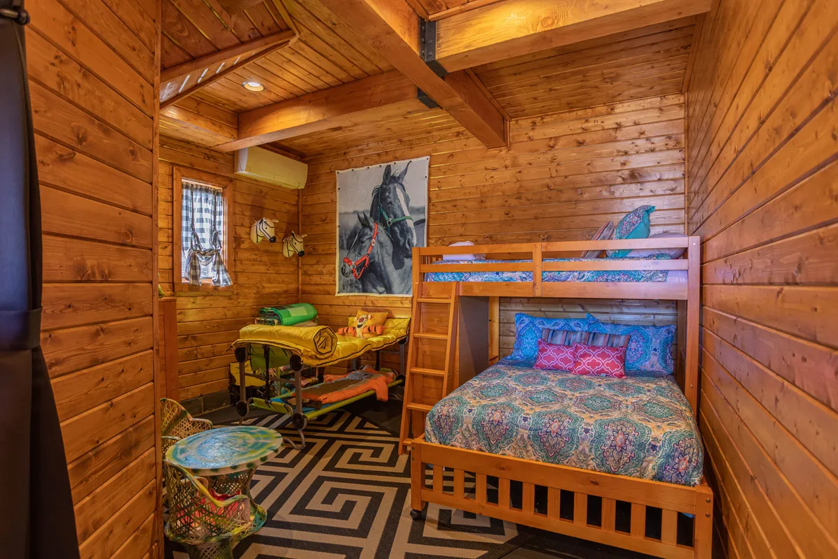 A whimsical bunk bedroom featuring a bunk bed with colorful bedding, playful horse-themed artwork, and a patterned rug. The room exudes a sense of fun and imagination, perfect for kids to play, read, or unwind.